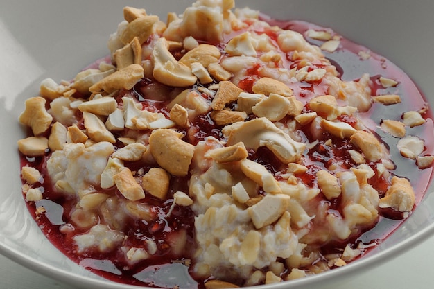 Bouillie avec confiture et noix sur une plaque blanche sur fond blanc