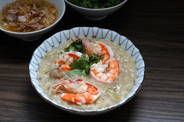 Bouillie de crevettes dans un bol avec de l'ail frit et de la coriandre à l'huile sur une table en bois