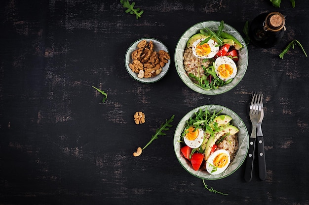 Bouillie de flocons d'avoine pour le petit-déjeuner avec œufs durs, tomates, avocat et herbes vertes Alimentation saine et équilibrée Vue de dessus mise à plat