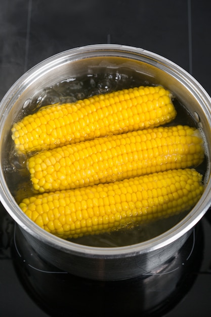 Bouillie de maïs en épi dans une casserole d'eau bouillante