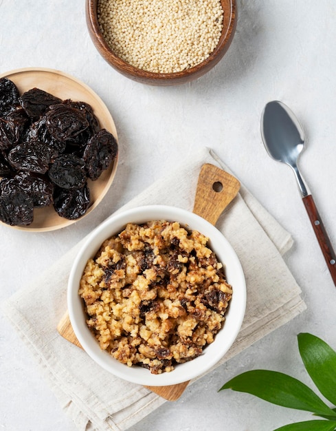 Bouillie de millet aux pruneaux dans un bol sur fond blanc avec du lait Le concept d'un délicieux petit-déjeuner nutritif et sain Aliments diététiques et énergétiques