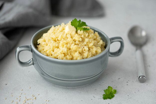 Bouillie de millet bouilli avec du beurre et des graines de sésame dans une assiette grise