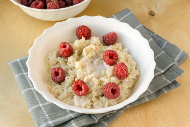 Bouillie D'orge Au Lait Avec Du Beurre Et Des Framboises Dans Un Bol Blanc Sur Fond De Bois.