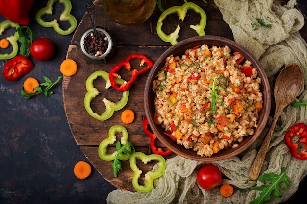 Bouillie d'orge végétarienne perle friable avec des légumes dans un fond sombre. Mise à plat. Vue de dessus