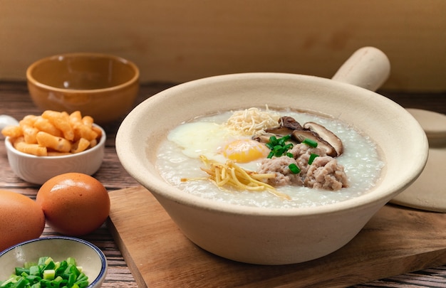 Bouillie de riz avec œuf à la coque et œuf émincé dans un plat d'accompagnement en argile blanche avec patongo croustillant bâton de pâte frite petit-déjeuner thaïlandais