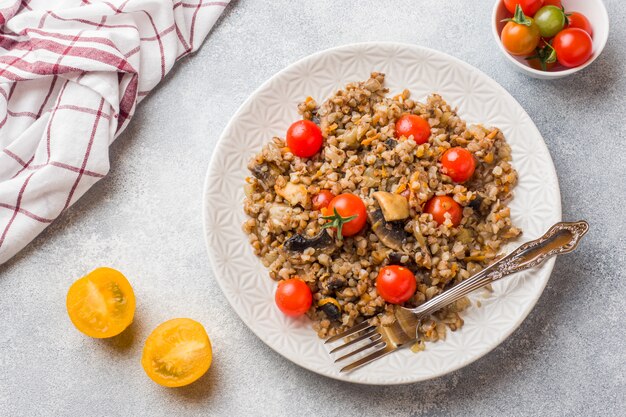 Bouillie de sarrasin aux champignons et tomates cerises sur une assiette.