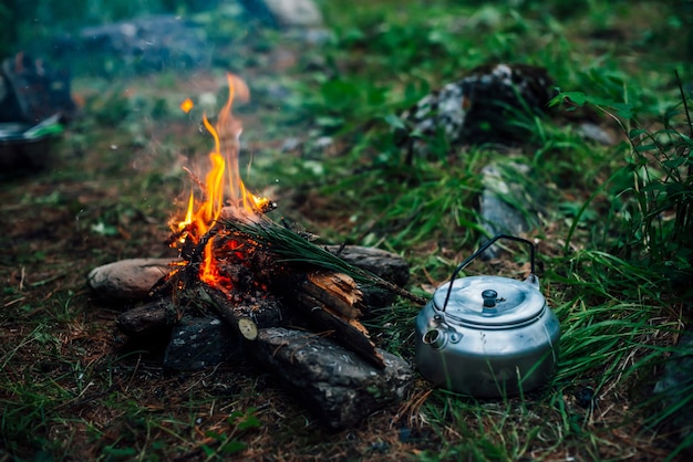 Bouilloire de camping près d'un petit feu de camp