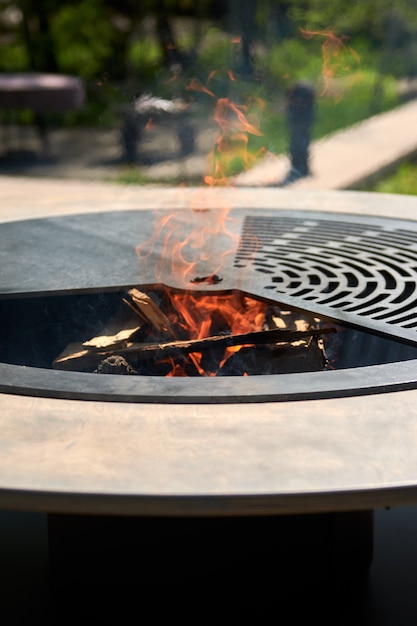 Bouilloire grill avec grille en fonte avec flammes table ronde surface de cuisson barbecue chaud sur l'arrière-cour