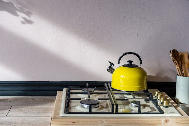 Une bouilloire jaune avec une poignée noire se dresse sur une cuisinière à gaz.