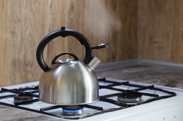 Bouilloire moderne en métal argenté sur la cuisinière à gaz dans la cuisine