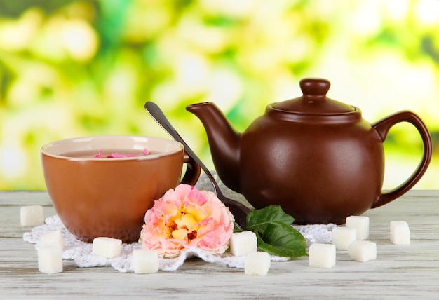 Bouilloire et tasse de thé de thé rose à bord sur une serviette sur une table en bois sur fond de nature