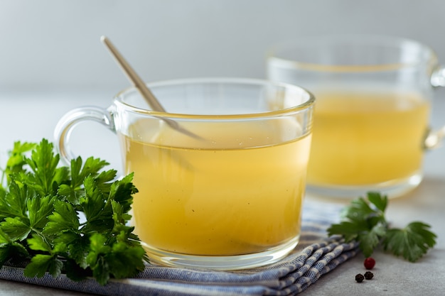 Bouillon d'os dans une tasse en verre sur fond clair, mise au point sélective