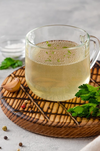 Bouillon de poulet dans une tasse en verre avec de l'ail persil et d'autres épices Copier l'espace