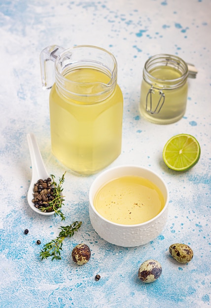 Bouillon de poulet fait maison servi avec thym, citron vert et œuf de caille