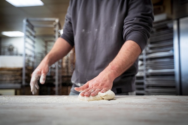 Boulanger dans la cuisine avec une main sur la pâte