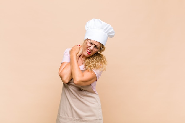 Boulanger de femme d'âge moyen se sentant anxieux, malade, malade et malheureux, souffrant de maux d'estomac ou de grippe