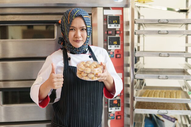 Boulanger femme musulmane debout avec sa boulangerie