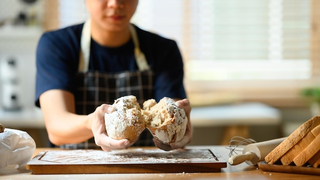 Boulanger mâle dans les mains du tablier tenant du pain au levain Aliments sains concept traditionnel de boulangerie et de pâtisserie