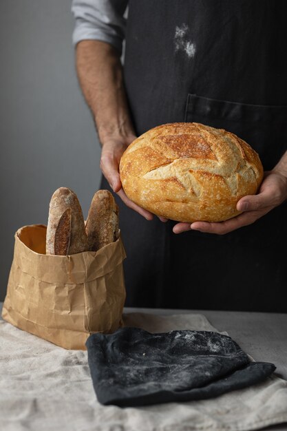 Un boulanger mâle européen adulte tient un pain frais rond dans ses mains un homme dans une boulangerie tient un