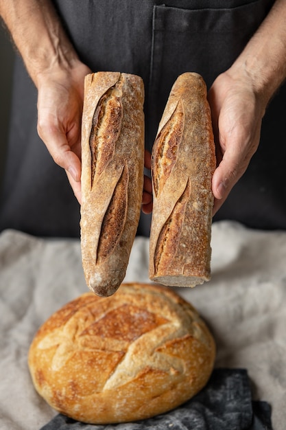 Un boulanger mâle européen adulte tient un pain frais rond dans ses mains un homme dans une boulangerie tient un