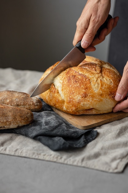 Un boulanger mâle européen adulte tient un pain frais rond dans ses mains un homme dans une boulangerie tient un