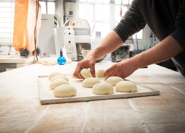 Boulanger préparant la pâte pour faire du pain sur une table en bois dans la cuisine