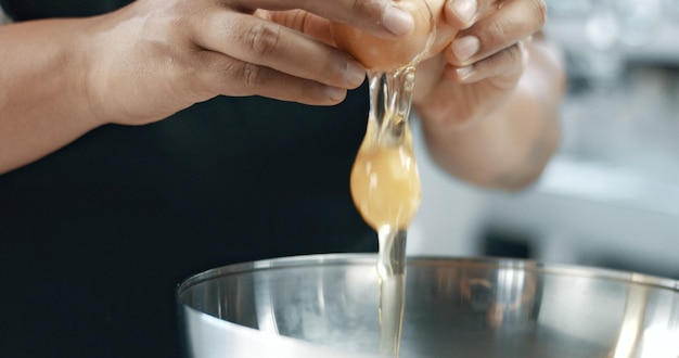 Un boulanger de race mixte fait un gâteau casser des œufs