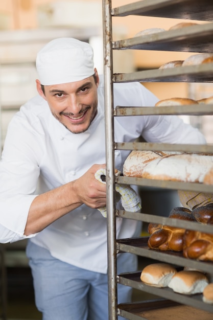 Boulanger souriant en poussant le plateau de pain