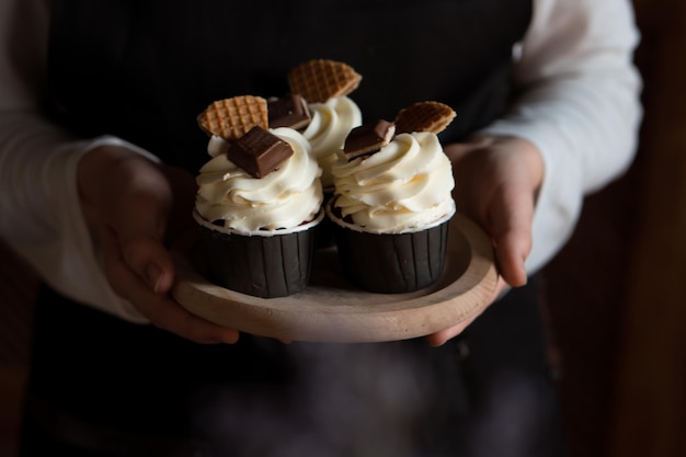 boulanger tenant dans les mains des cupcakes frais avec de la crème au fromage, décorés de chocolat