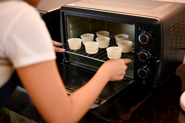 Une boulangère mettant un plateau de cupcakes frais dans le four cuire des cupcakes au four