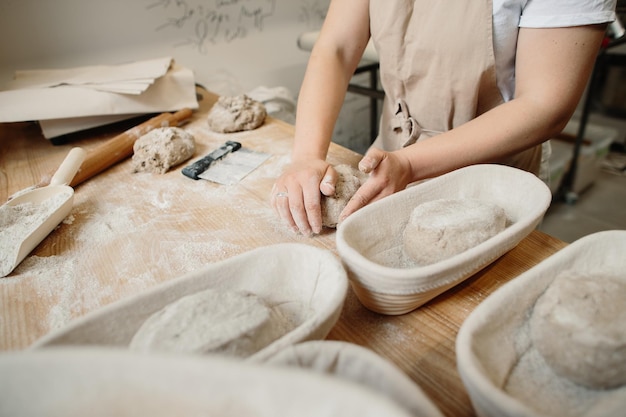 Une boulangère pétrit la pâte et la met sous une forme en bois Concept de boulangerie