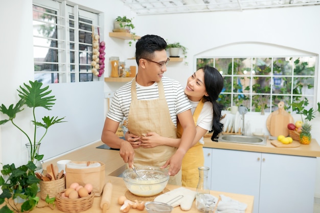 Boulangerie de cuisson de couple dans la salle de cuisine, jeune homme et femme asiatiques ensemble faisant le gâteau et le pain avec l'oeuf,