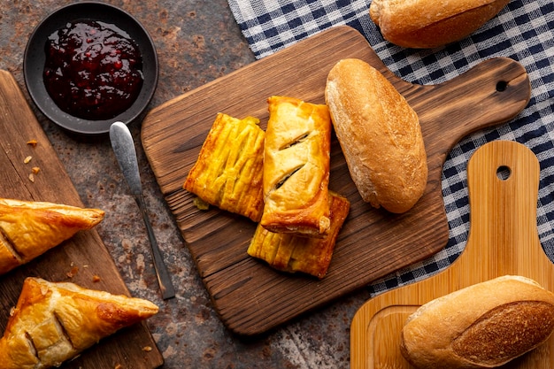 Boulangerie divers types de pain frais parfumé dans une planche à découper en bois sur une serviette de table vue de dessus concept de conception de thème alimentaire à plat