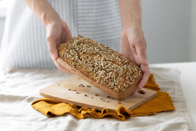 Boulangerie européenne tenant du pain de sarrasin femme blanche dans un tablier léger tenant du levain fait maison