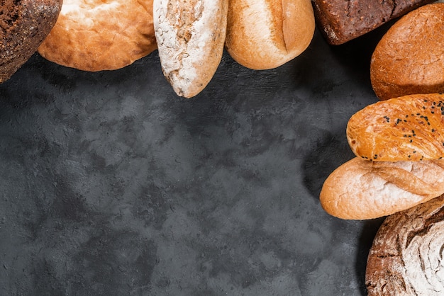 Boulangerie fraîche, miches de pain croustillantes rustiques sur fond de pierre noire. Vue de dessus