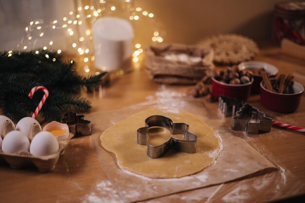 Boulangerie maison cuisinant des bonbons festifs traditionnels coupant des biscuits de pâte de pain d'épice crue sur du bois
