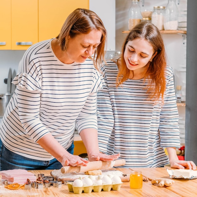 Boulangerie maison fille regardant sa mère rouler la pâte à faire des biscuits au pain d'épice