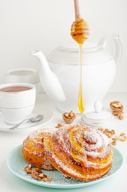 Boulangerie maison. Verser le miel sur un petit pain roulé sucré aux noix et noix de coco râpée sur blanc