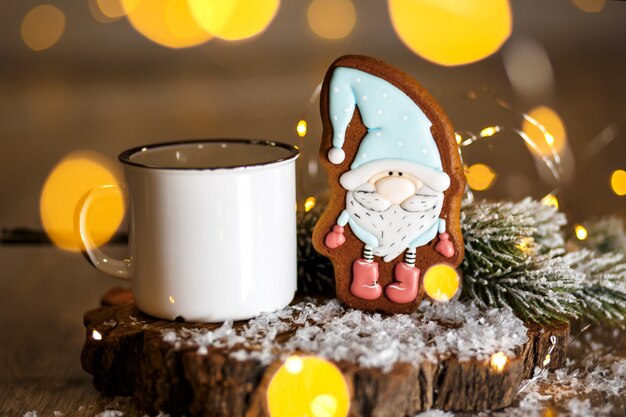 Boulangerie traditionnelle de vacances. Petit gnome de conte de fées en pain d'épice à la décoration chaleureuse avec guirlandes et tasse de café chaud