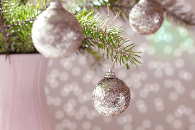 Boule argentée brillante de Noël sur une branche verte d'épinette sur un fond clair