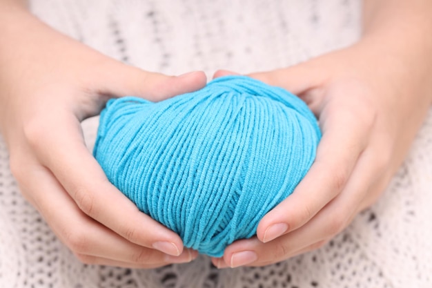 Boule bleue de laine dans les mains sur le fond d'une nappe tricotée blanche. Photo de haute qualité