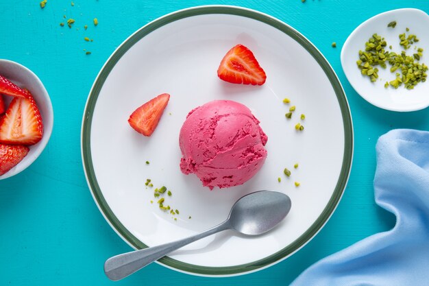 Boule De Crème Glacée à La Fraise Fruitée Servie Sur Assiette Avec Des Fruits Et Des Pistaches. Vue De Dessus.