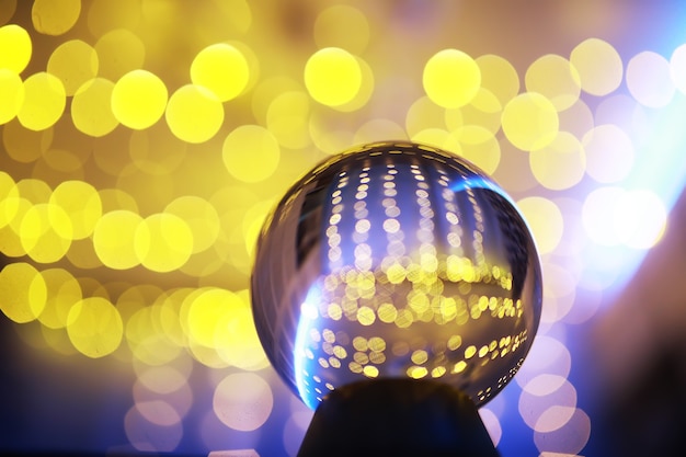 Boule de cristal au sol avec bokeh, lumières derrière. Boule de verre avec lumière bokeh colorée, concept de célébration du nouvel an.