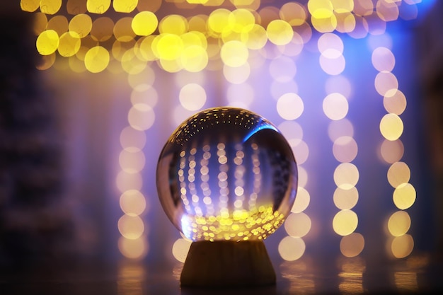 Boule de cristal au sol avec bokeh, lumières derrière. Boule de verre avec lumière bokeh colorée, concept de célébration du nouvel an.