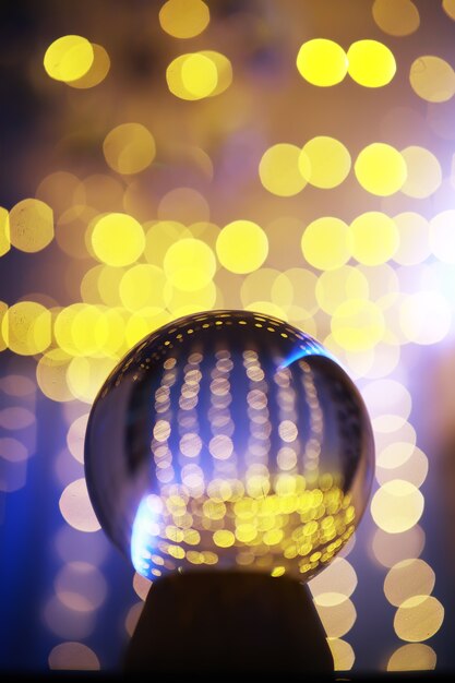 Boule de cristal au sol avec bokeh, lumières derrière. Boule de verre avec lumière bokeh colorée, concept de célébration du nouvel an.