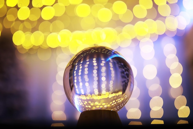 Boule de cristal au sol avec bokeh, lumières derrière. Boule de verre avec lumière bokeh colorée, concept de célébration du nouvel an.