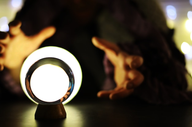 Photo boule de cristal sur la table avec bokeh, lumières derrière. boule de verre avec lumière bokeh colorée, concept de prédiction.