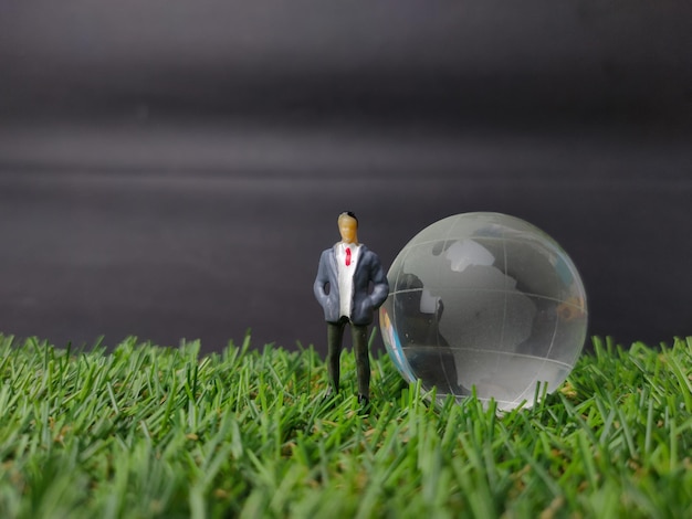 Boule de cristal de terre avec des personnes miniatures sur un fond d'herbe avec espace de copie