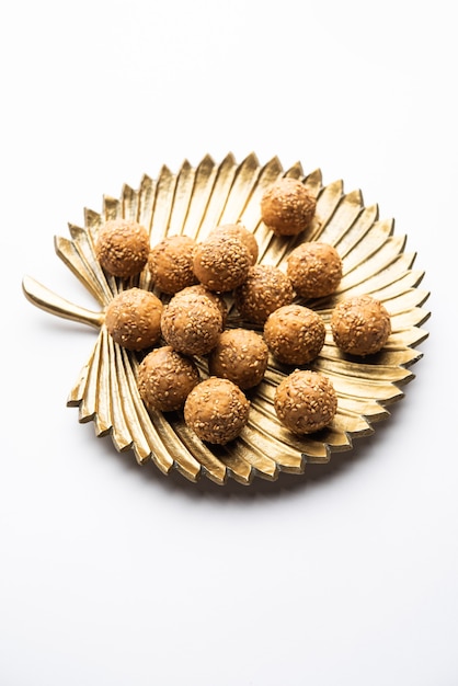 Boule de jaggery aux graines de sésame ou til ke laddo et tilgul ou til gul laddu servi dans un bol pour le festival Makar Sankranti en Inde