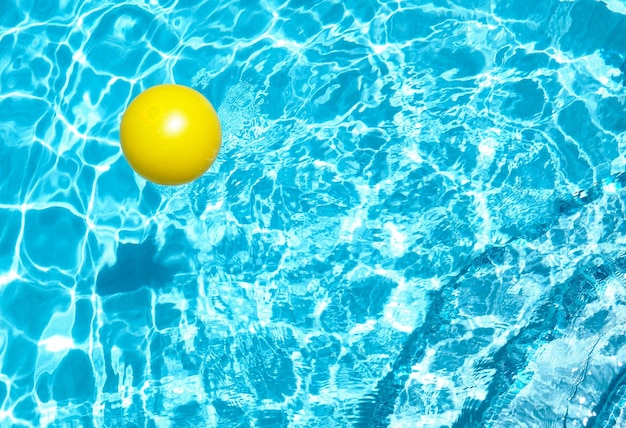 Boule jaune flottant dans une piscine d'eau cristalline